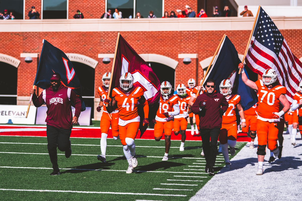 Virginia Tech WR coach Fontel Mines carries a UVA flag as the Hokies come onto the field.

Mines was a former wide receiver for the Cavaliers.

📸 <a href="/HokiesFB/">Virginia Tech Football</a>