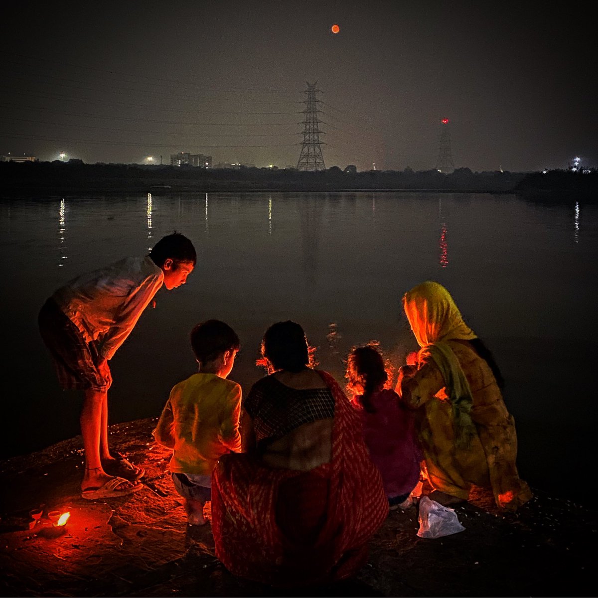 A group of Hindu Devotees pray on the bank of river Yamuna as the ‘Blood Moon’ is seen during the Total Lunar Eclipse in New Delhi, India on Tuesday, November 8, 2022. #BloodMoon #LunarEclipse2022 #Delhi #India #Asia #DailyLife #Photojournalism #ShotoniPhone