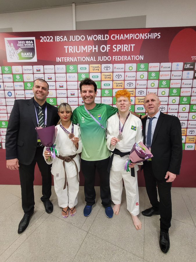 Foto dos dois atletas do jud medalhistas ao lado dos tcnicos.