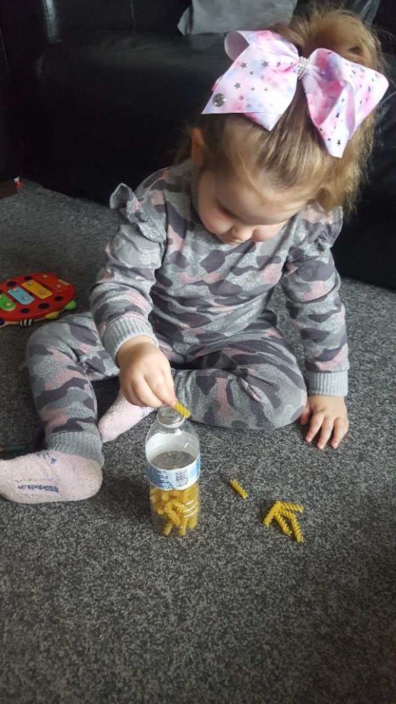 child orgainising pasta into a bottle