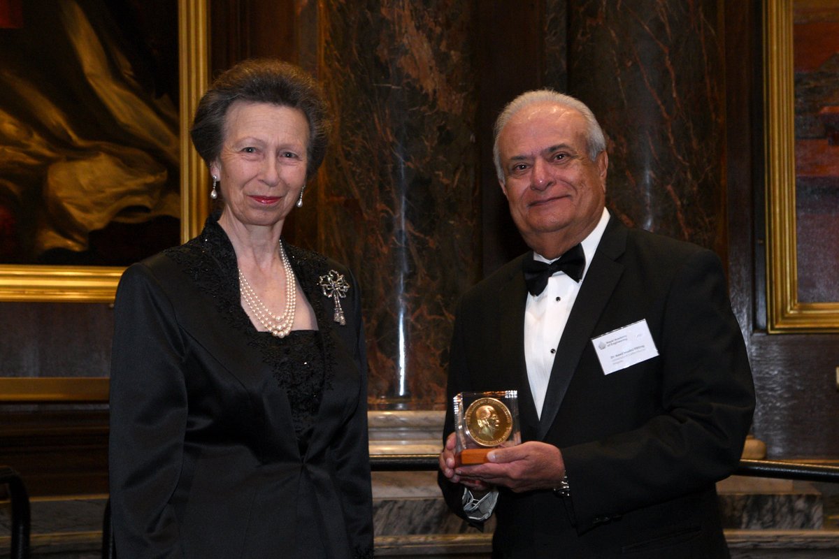 HRH The Princess Royal stands next to Dr Asad Madni in black tie, holding a medal.