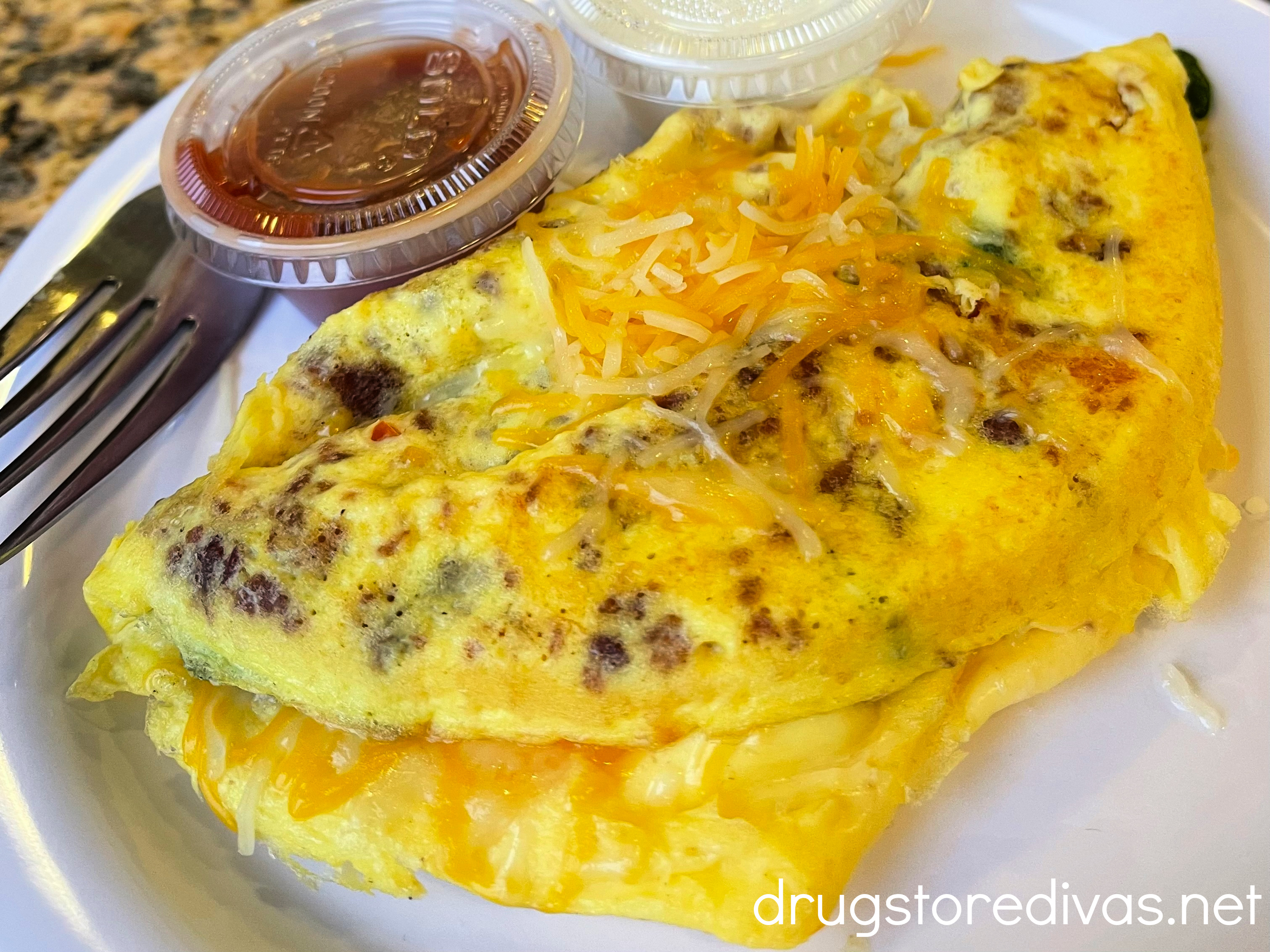 An omelet on a plate with fresh salsa and sour cream.