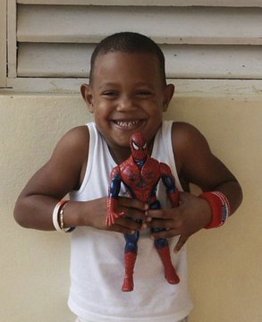 A young Julio Rodríguez smiles while holding a Spiderman toy. 