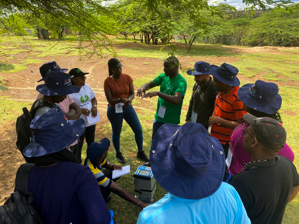 GDCKenya's tweet photo. GDC Geophysicist, Joseph Gichira (in green), explains the process of collecting data using a Gravimeter, which is used for gravity prospecting in geothermal exploration. #GROGTPShortCourseVI https://t.co/utJRA6d8YH