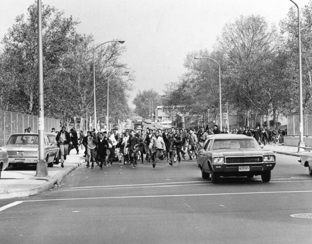 A black and white photo of students marching down a street.