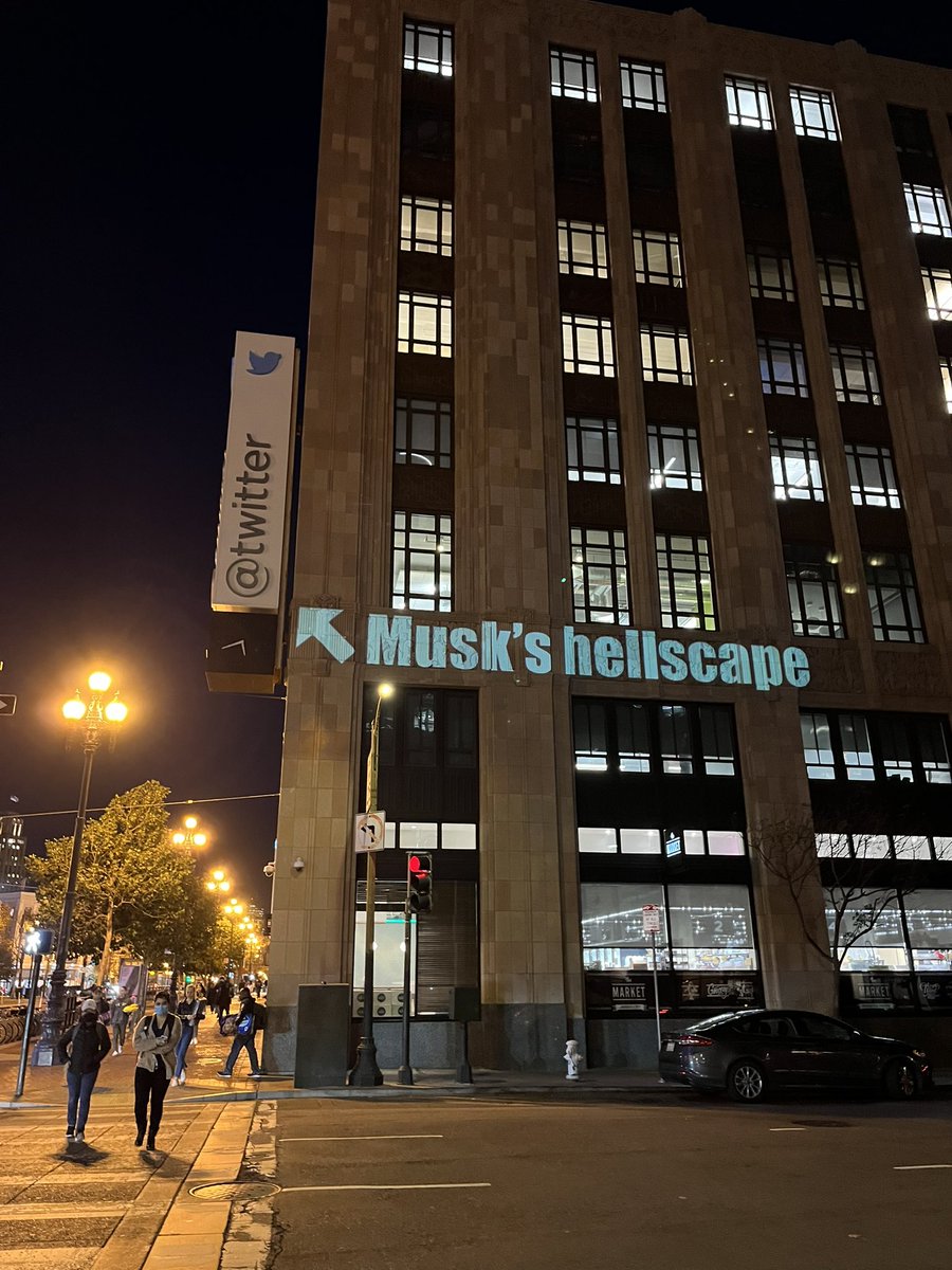 Gia_Vang's tweet image. Someone is projecting multiple messages onto Twitter headquarters building in SF from a neighboring building.