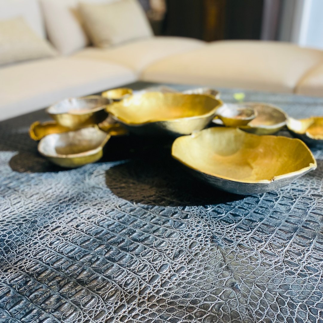 Our Greystoke Cocktail Table features a top with faux crocodile hide in Greystoke black and a metal base in an Aztec gold finish. bit.ly/3UbRP34  #johnrichard #dreamhome #modernhome #decor #luxurydesign #decoration #homedesign