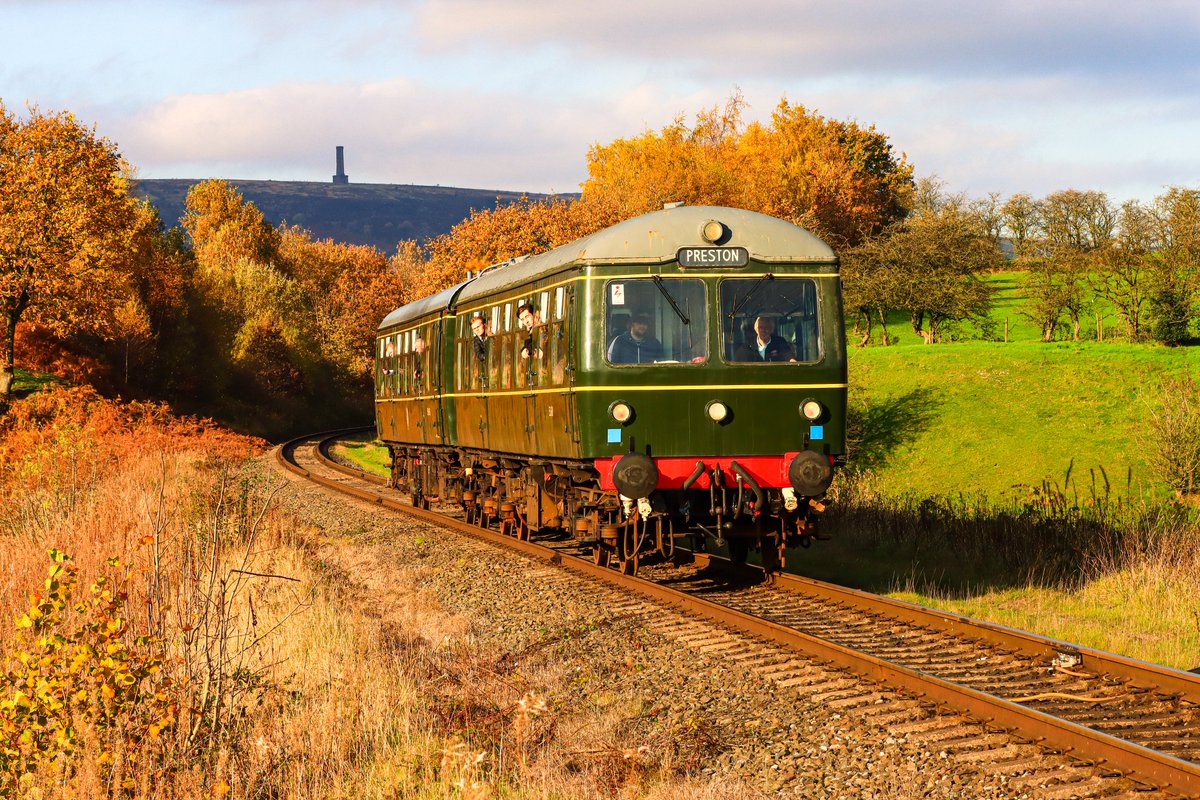 andrew_herny's tweet image. In the bright afternoon sunshine, 'Cravens' Class 105 DMU descends toward Burrs Country Park Halt during the @eastlancsrly DMU Gala with a service to Heywood,  with Peel Tower on Holcombe Hill in the distant background. #EastLancsRailway #ELRDMU #Class105 #HeritageRail #DMU