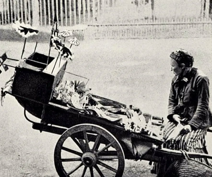 A toy seller in King William Street , outside the Royal Naval College in Greenwich London. 1887 There were 30,000 street sellers known as costermongers in the late 1800s selling from a hand pushed barrow or a cart pulled by a donkey.