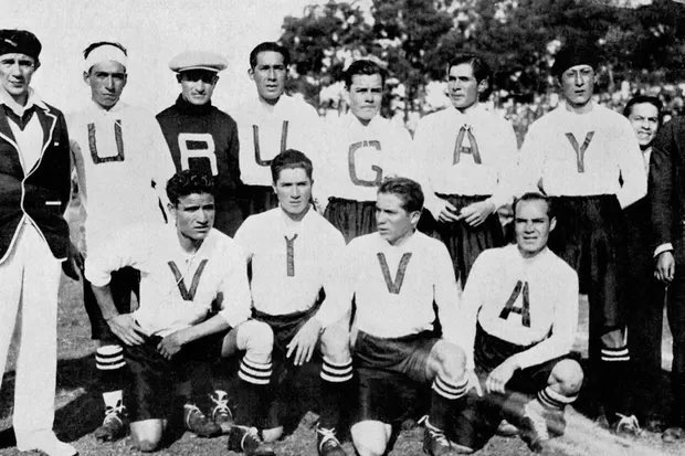 Foto da seleção do Uruguai, em preto e branco. 11 homens estão em de frente pra foto, 7 em pé e 4 sentados. Vestindo a camisa de letrinhas que formaria o nome Uruguay