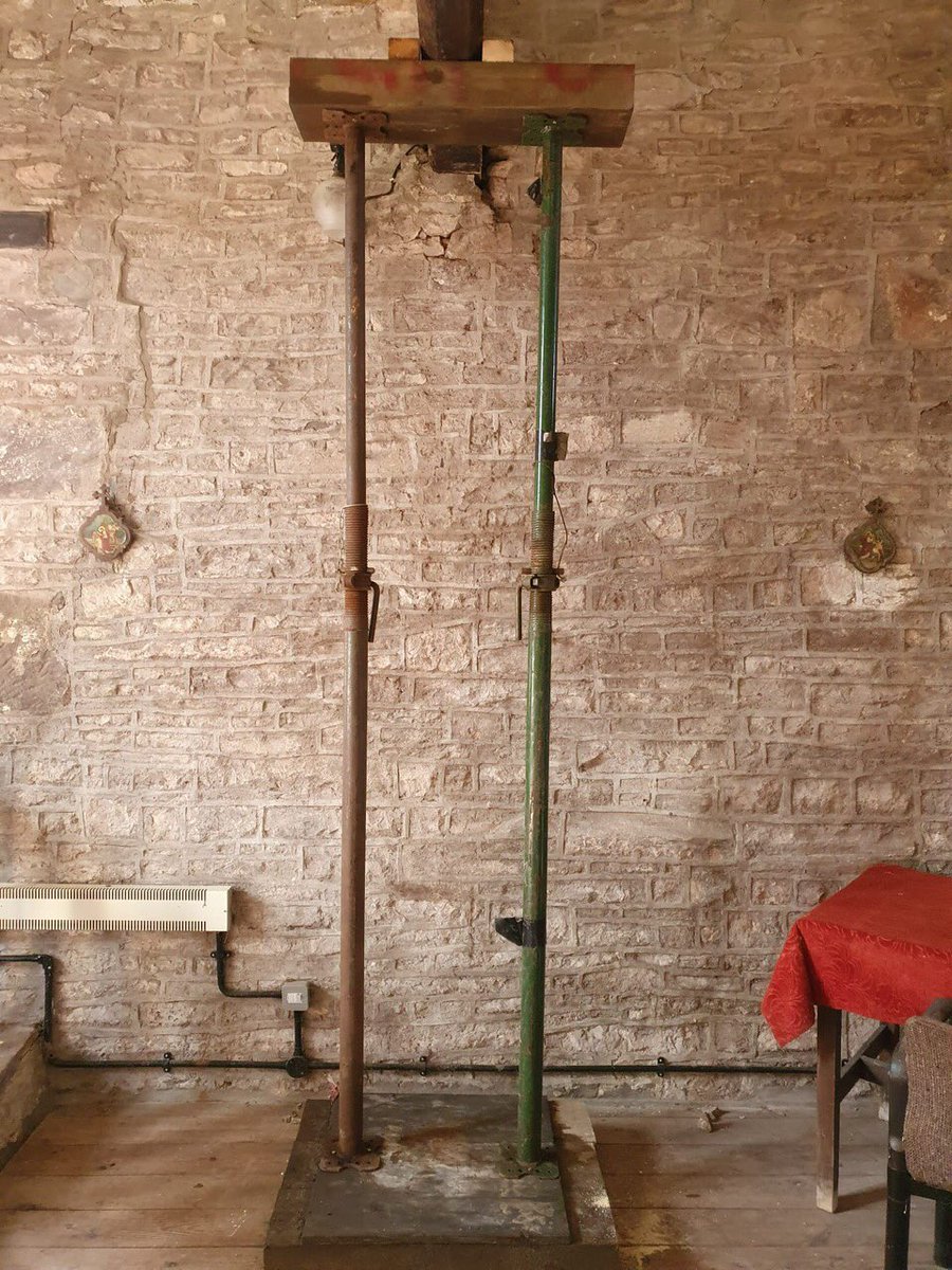 Two scaffold poles and a wooden board propping up a timber beam.