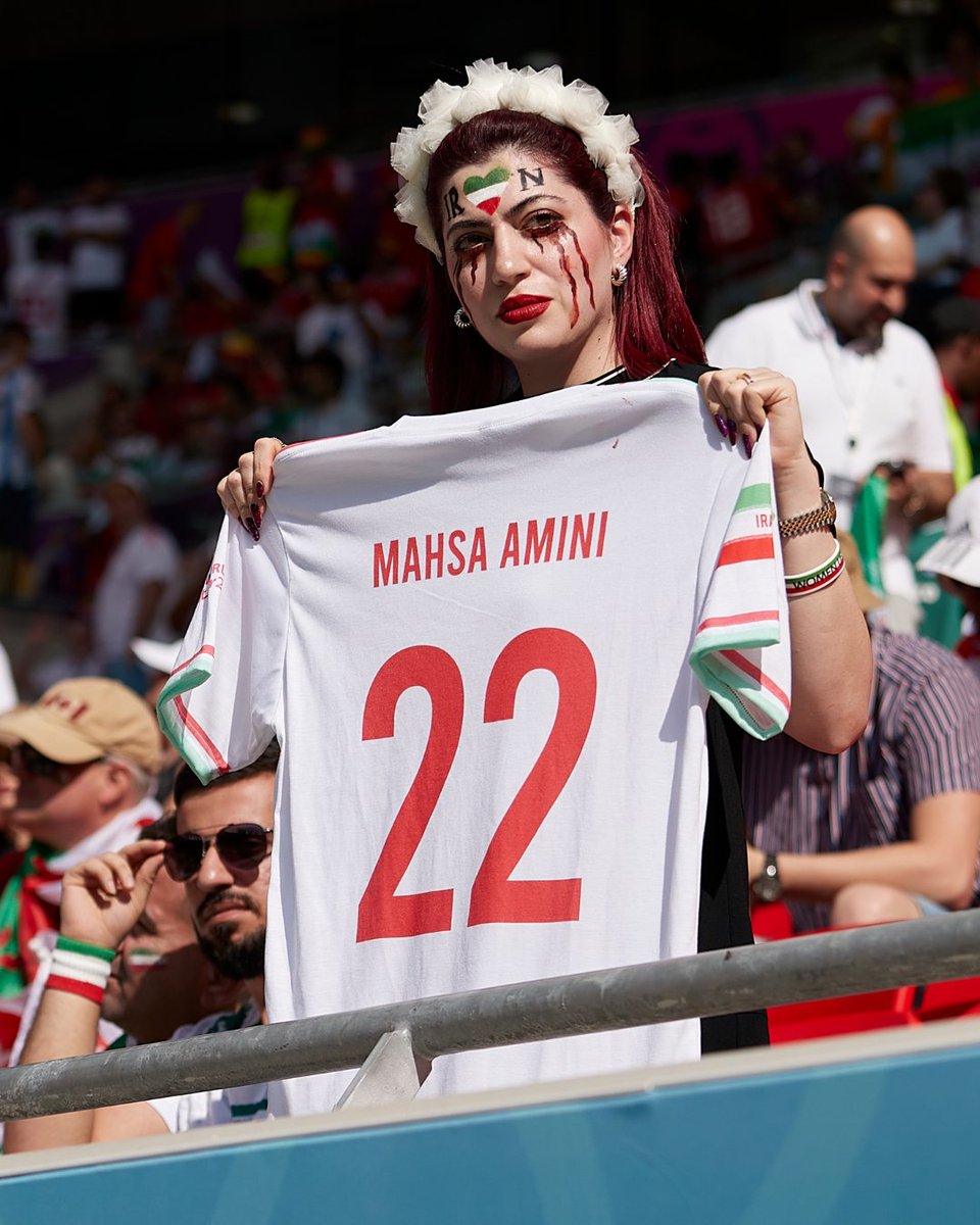 iccwomen's tweet photo. This Iran fan held up a shirt with the name Mahsa Amini, a 22-year-old who died days after being arrested and beaten by Iran's police for allegedly not adhering to the nation's dress code for women. 

📸: IMAGO https://t.co/M3tjaSwWEw