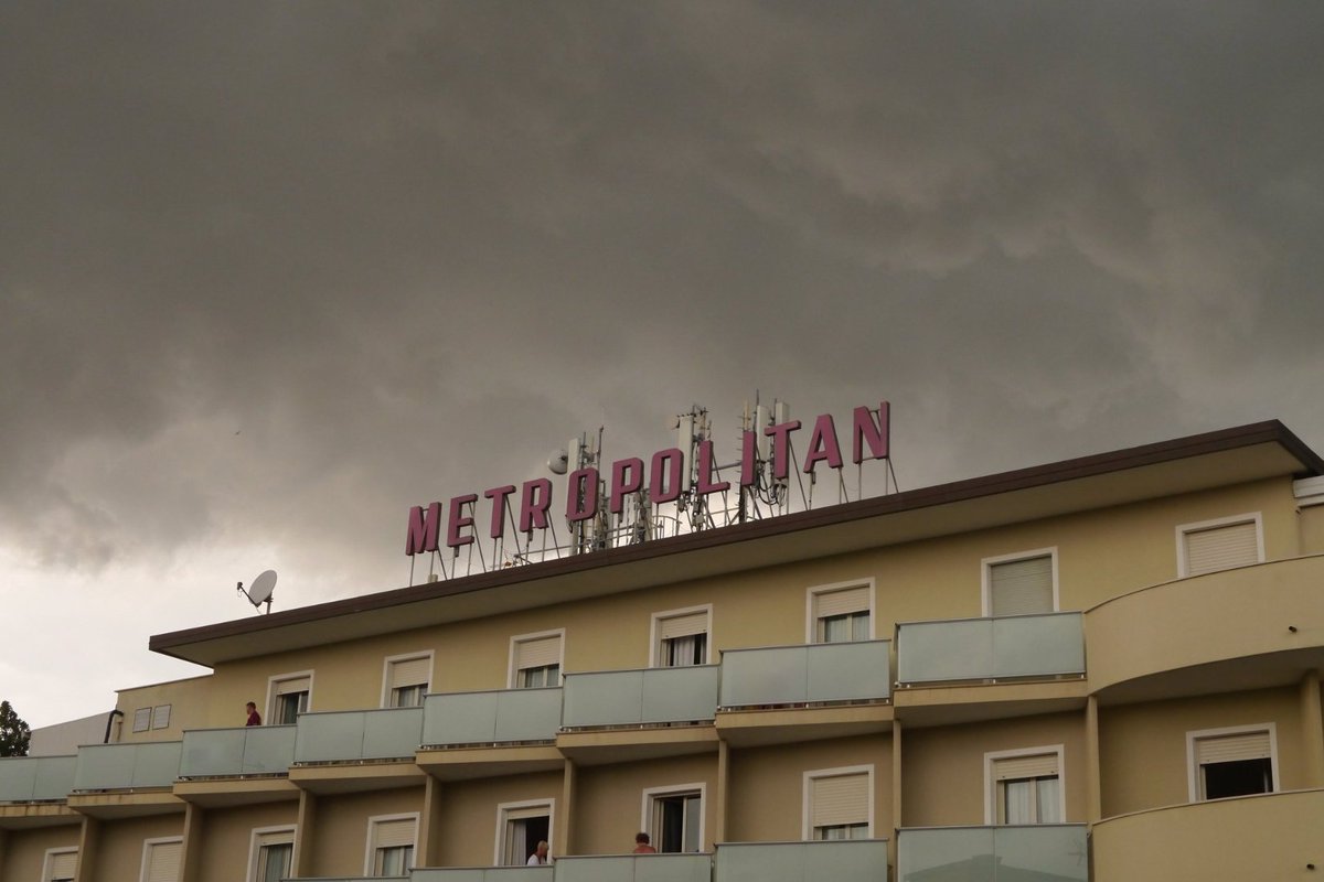 photo of a yellow building against a grey cloud, the sign in red reads metropolitan