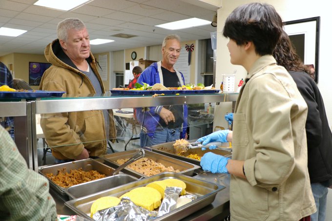 image of two adults in food line with two high school students serving food