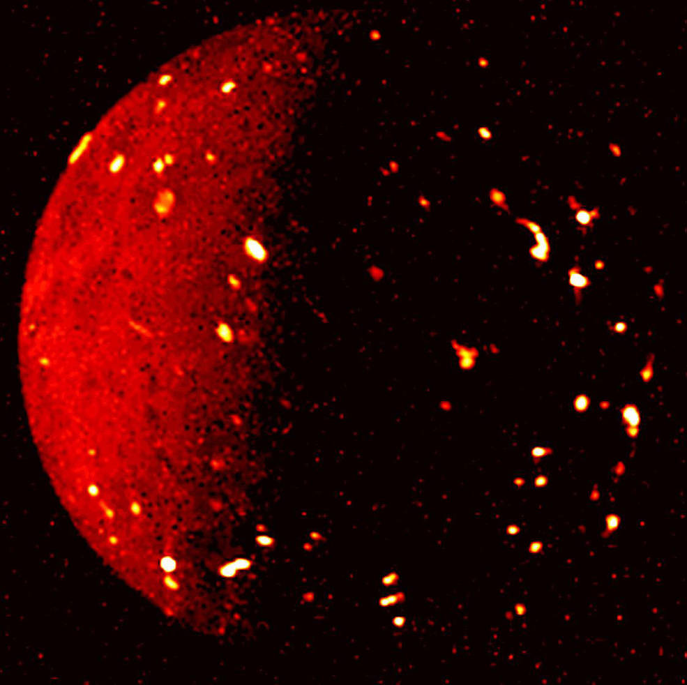 A close, full-disc view of Io, with one side illuminated by sunlight. On both the day and night sides, bright red spots are glowing.