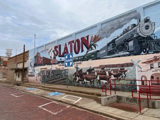 Mike_Hixenbaugh's tweet photo. When you’re the new kid in Slaton, Texas, this mural—painted in 1998 by prisoners—is one of the first things you notice. It shows Black workers toiling in a cotton field as a white farmer peers down from the seat of a tractor, along with the slogan “Slaton: Your Kind Of Town.” https://t.co/7RxqL6vA8e