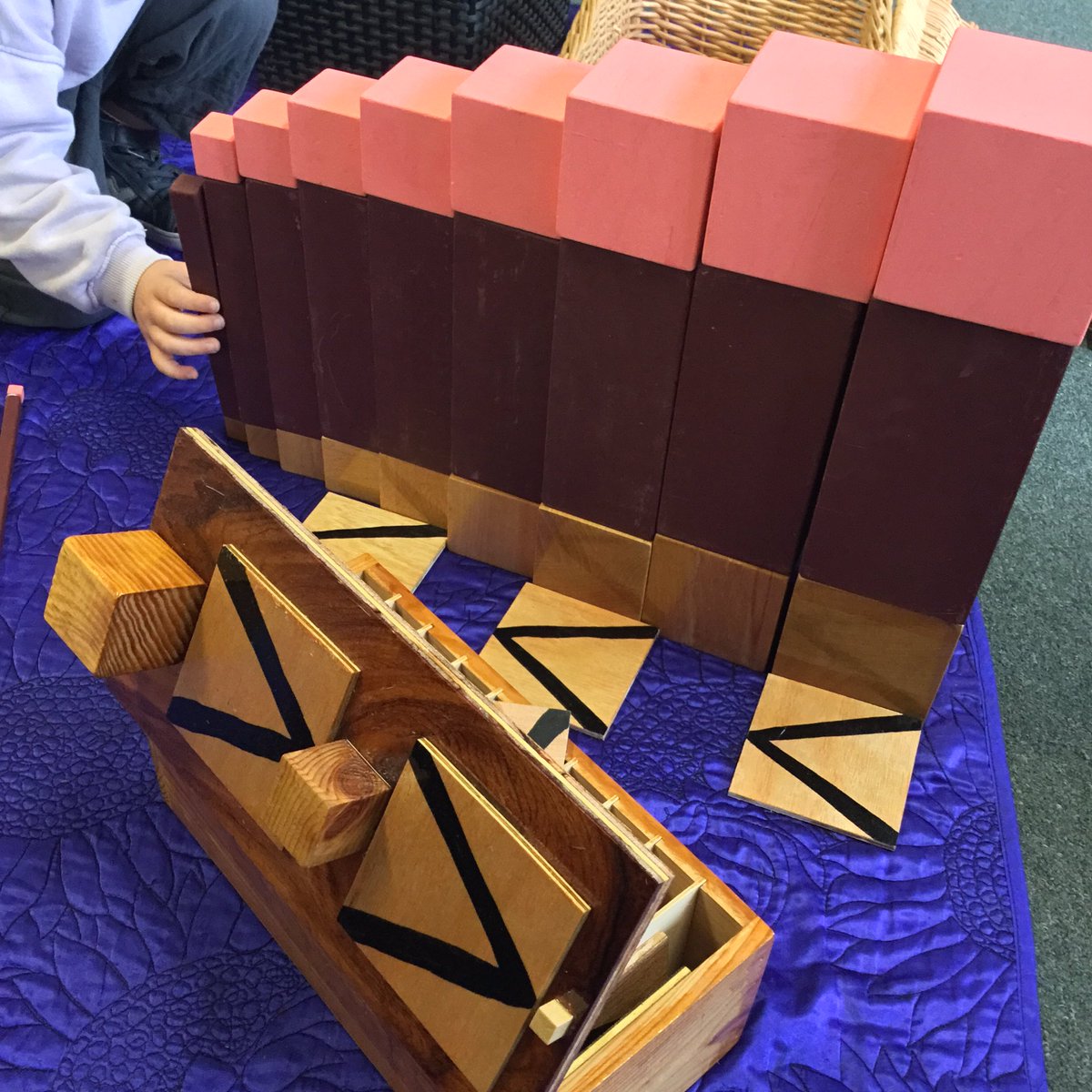 Joolone's tweet photo. A #nursery child independently plays with the Magnitude Box. 
He builds a series of towers by combining the #Pinktower and #Brownstairs in descending order on a rug.
He takes the symbols from the box and places them to express the direction and flow of magnitude.
#Montessori https://t.co/MPihN70GZ0