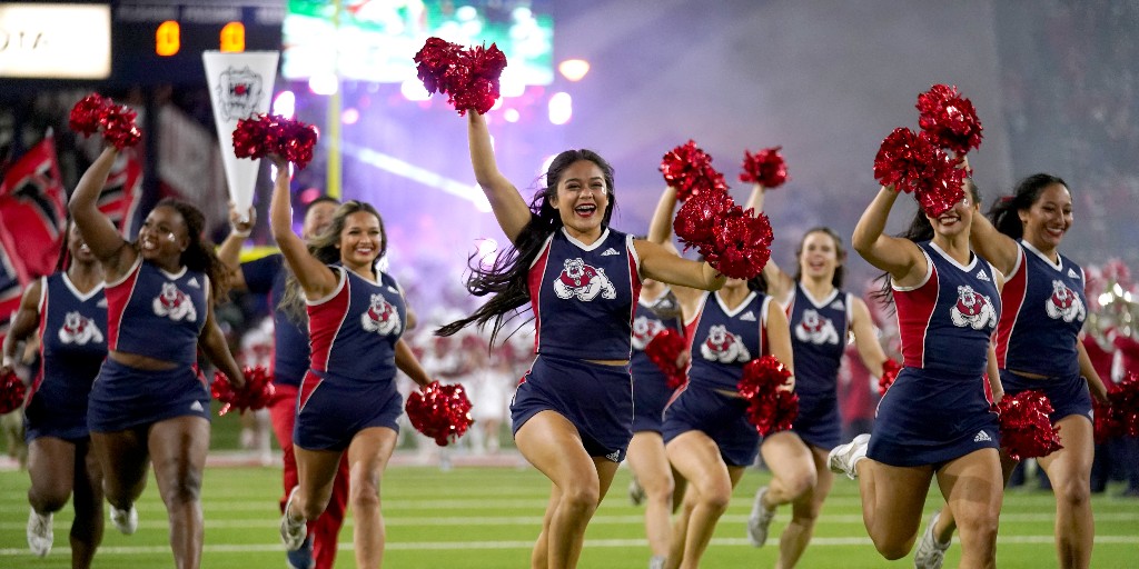 Fresno State cheerleaders smile as they run across the field. 