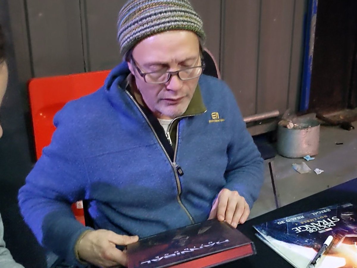 Evalie3689's tweet photo. #MadsMikkelsen put on his glasses so that he could examine @solamentenic's copy of the Hannibal Art Book by @PrintedinBlood!! He thought it was cool! He said he couldn't believe how much fan art is out there! #MadsInManchester https://t.co/QS1s2Ni9WL