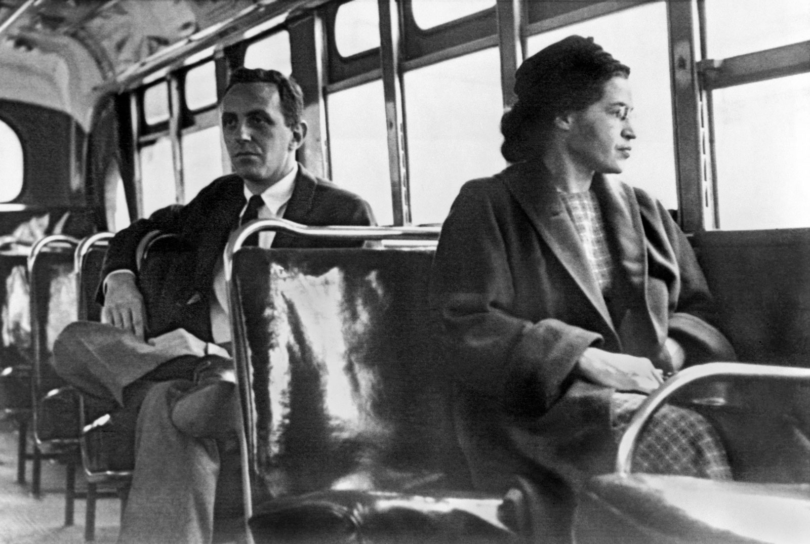 Black and white photo of Rosa Parks sitting in a bus seat and looking out of the window.
