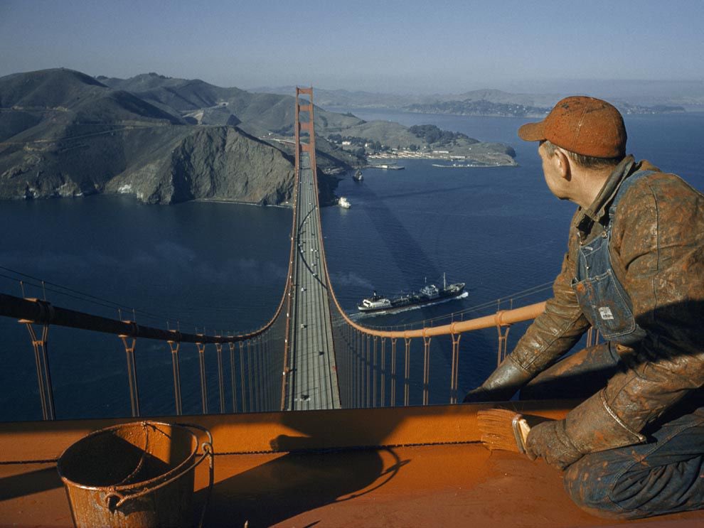 A worker paints the Golden Gate Bridge with a fresh coat of its iconic orange color, 1956