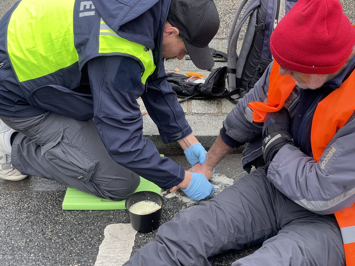 Ein Mitarbeiter der Münchner Polizei löst eine auf der Fahrbahn festgeklebte Hand. 6 #Klimaaktivisten der #letztenGeneration hatten an einer Abfahrt des Luise-Kiesselbach-Tunnels protestiert. ⁦<a href="/BR24/">BR24</a>⁩