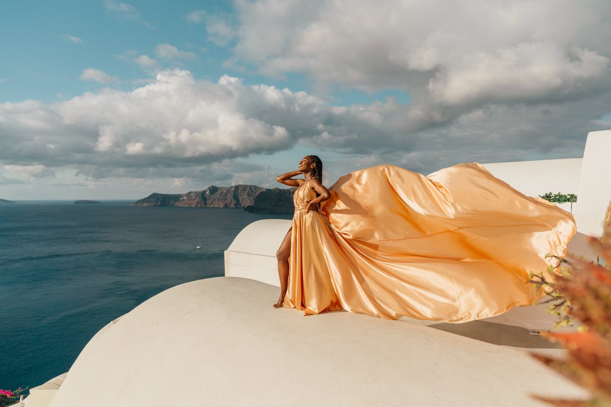 A black woman in a gold dress standing on a rooftop.