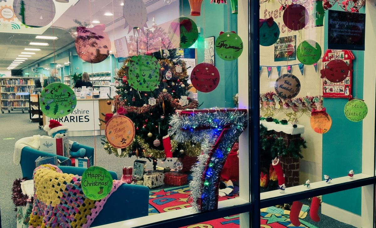 WBerksLibraries's tweet photo. Newbury Library's #Christmas window was revealed on Day 7 of #Newbury's Living Advent Calendar. Created in partnership with #Educafe, the theme is 'Everyone's Welcome', with festive greetings in lots of different languages hanging in the window and a cosy fireside scene inside. https://t.co/VjU8FKZLcO