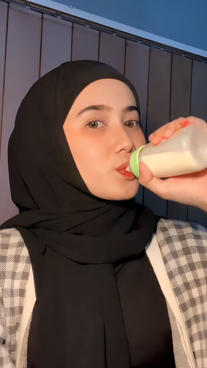 Cewek berjilbab hitam minum susu