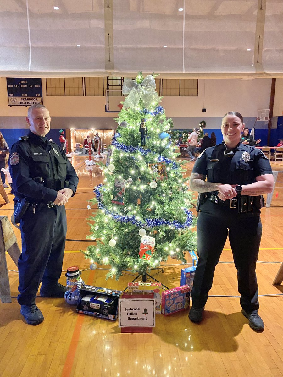 SeabrookNHPD's tweet photo. Officers Deshaies &amp; Storms with the #SeabrookNHPD Christmas tree at the @SeabrookRec Festival of Trees last night. Chief’s Secretary Judy &amp; Investigstions Secretary Jen did an awesome job decorating our tree! 🎄🖤💙🖤 https://t.co/cWYkPqm2HX