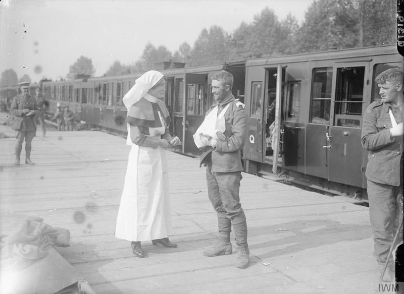 Hospital nurse, possibly of Queen Alexandra's Imperial Military Nursing Service (QAIMNS), in conversation with a wounded British soldier at Dernancourt, September 1916, by Ernest Brooks