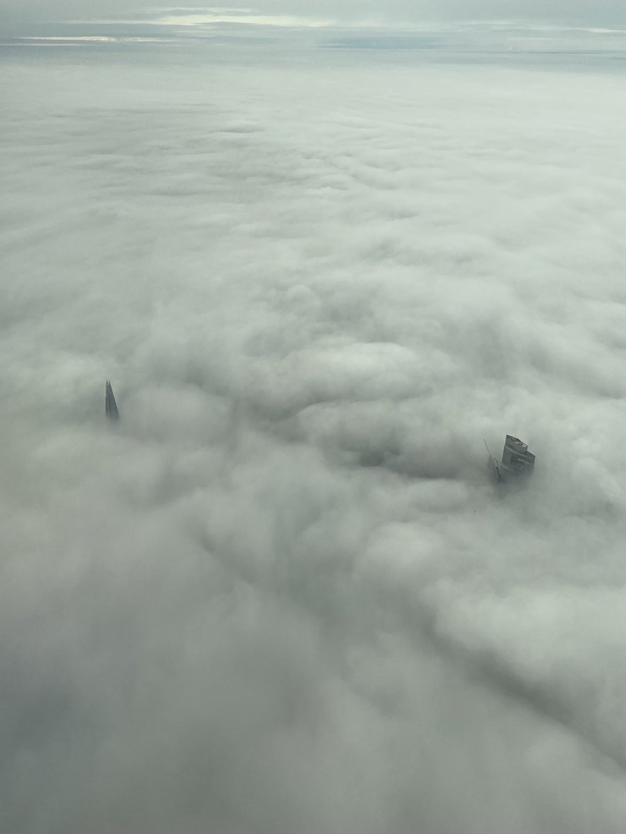 Extraordinary view flying into London, two solitary towers pierce the clouds.