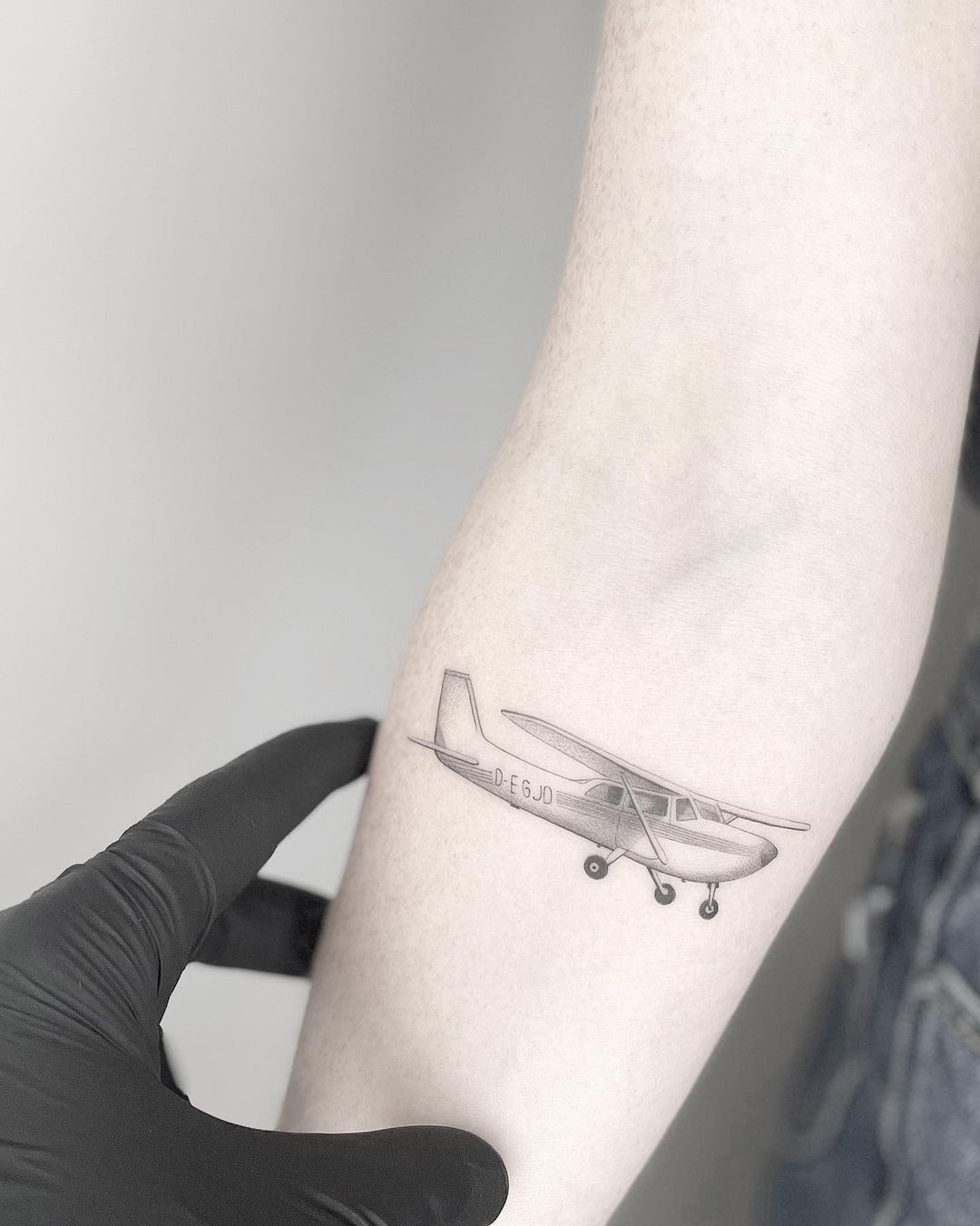 A minimal tatoo shows an airplane flying out of a suitcase to travel tattoo  idea | TattoosAI