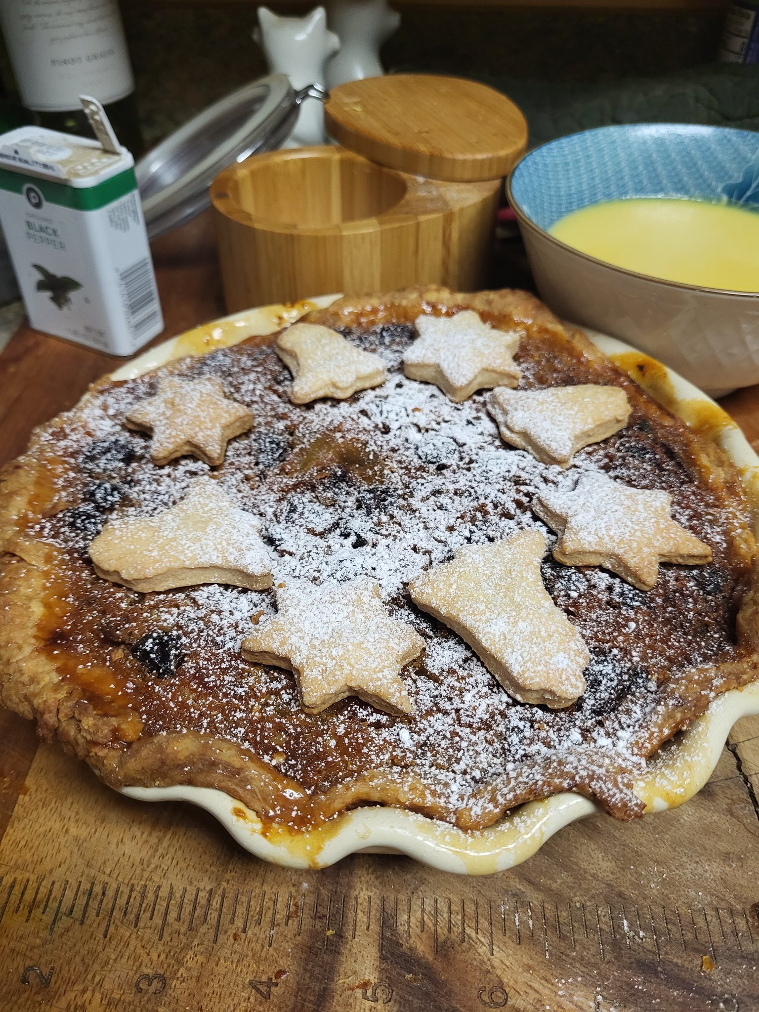 Minded fruit pie, round pie, stars and bells short crust decorations, rum butter in background.