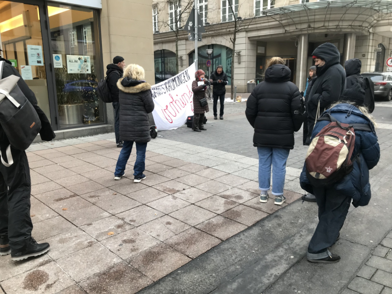 Menschen im Kreis vor dem Sozialrathaus in Frankfurt. Vor einem Transparent ZWANGSRÄUMUNGEN VERHINDERN spricht eine Person.