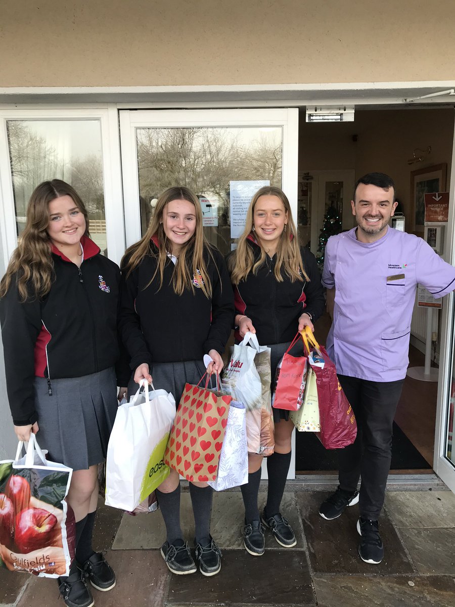 TY students Evie, Chloe and Sarah dropping off presents to Archersrath Nursing home residents. Receiving the gifts is Barry Williams, Activities Manager, past pupil of KCK