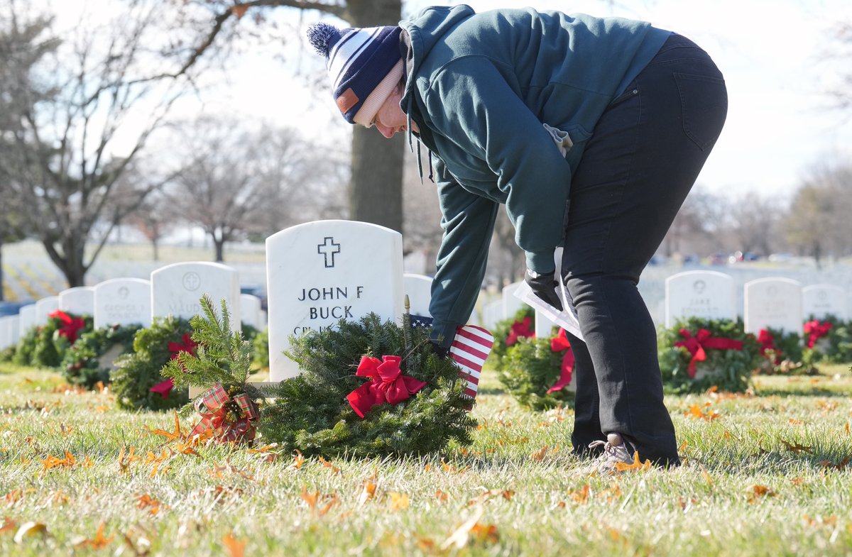 Volunteer Rachel Simmons places a wreath on the tomb of the late Hall of Fame broadcaster Jack Buck during Wreaths Across America at Jefferson Barracks National Cemetery in St. Louis on Saturday, December 17, 2022.