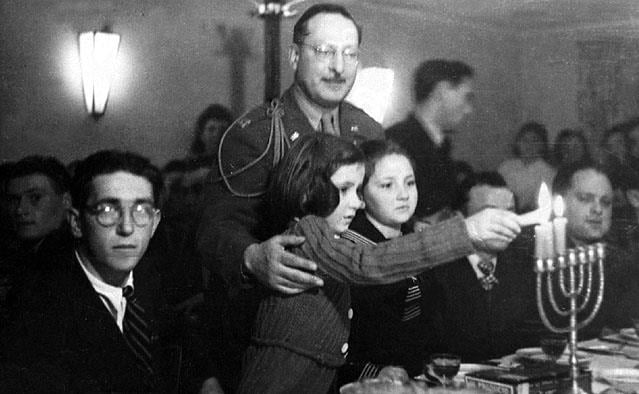 BluntBlackJew's tweet photo. Shoah survivors lighting Hanukkah candles in Fürstenfeldbruck displaced person camp, in the presence of the American military commander. Germany, 1945. https://t.co/C50NehLpGU
