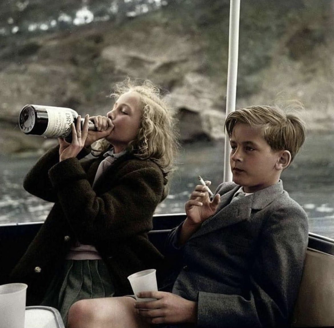 Thirteen-year-old Princess Yvonne of Sayn-Wittgenstein-Sayn in Germany is shown tipping back a bottle of Dry Sack sherry as her twelve-year-old brother Prince Alexander sits calmly by, his cigarette nearly finished. 1955