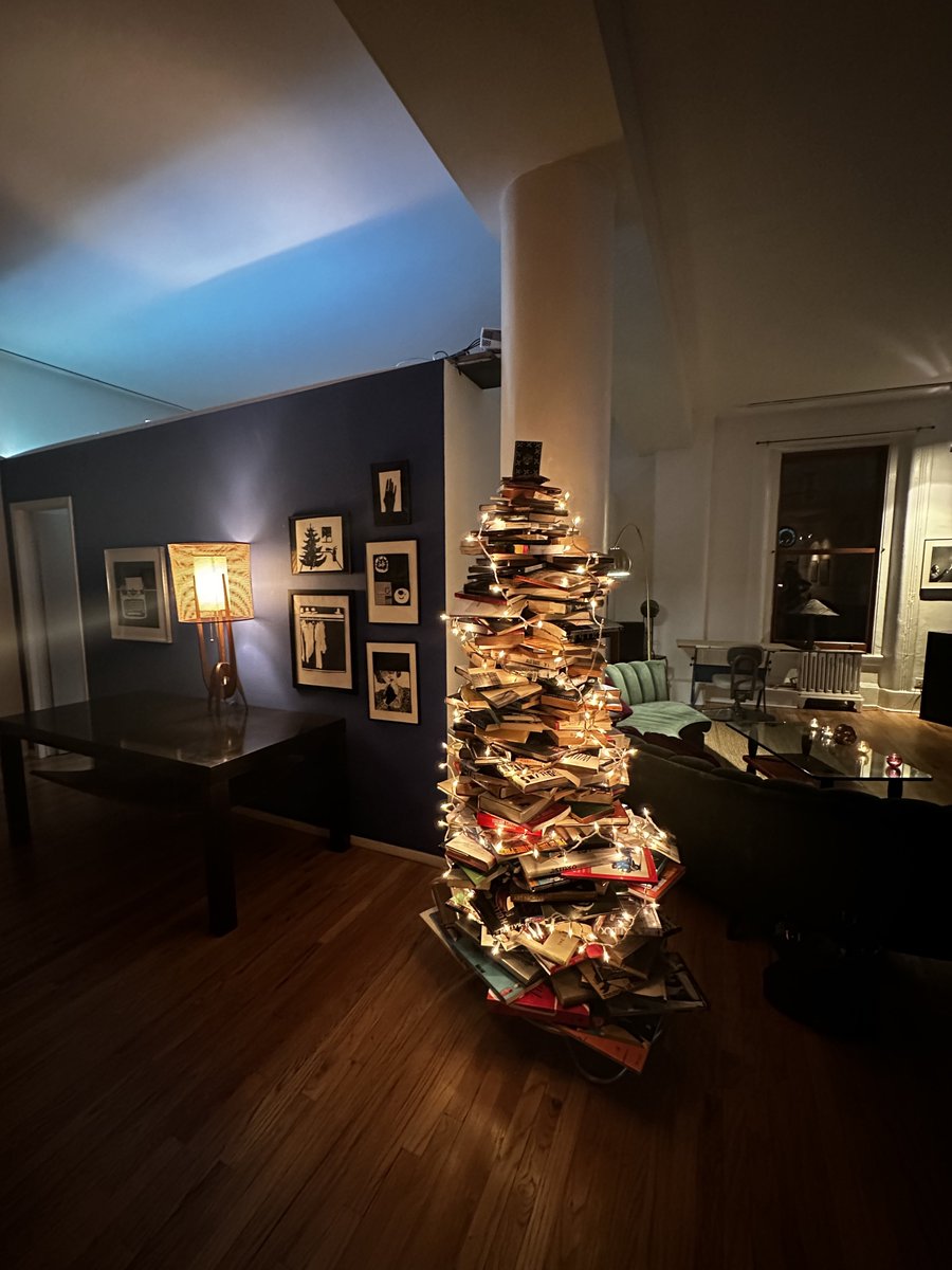 I’m at a party. This guy made a Christmas tree out of his books 🎄

There are no anchors for it: only gravity and careful stacking holding it together