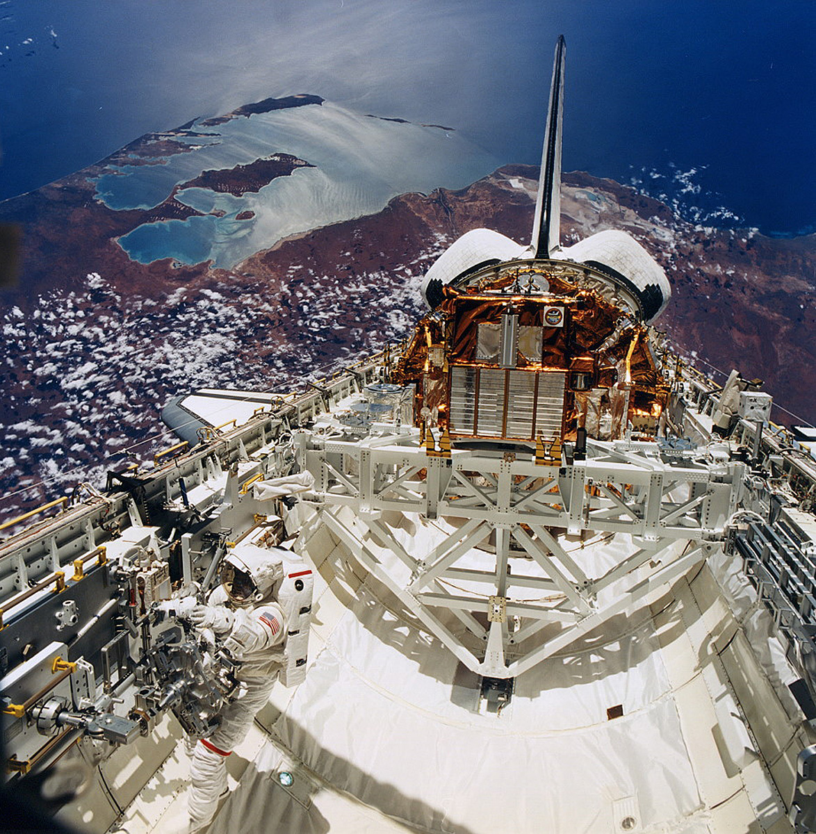 Leroy Chiao works in the payload bay of Endeavour during mission STS-72. Shark Bay, Australia looms in the background.