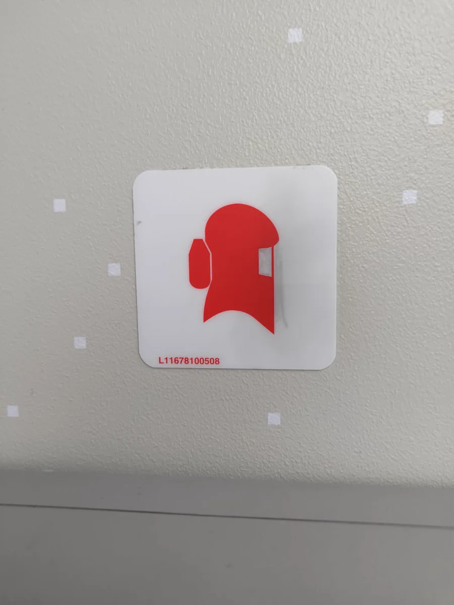 Sign on an Air Asiana flight. It contains an illustration of a full head mask, which looks similar to the popular Among Us videogame character.

A serial number L11678100508 is also displayed.