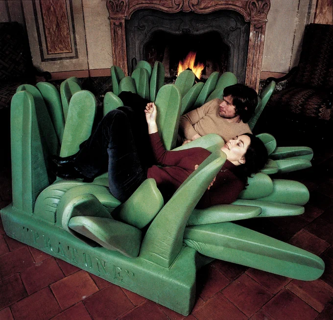 A photo of a man and woman lying and sinking into the chair. They are sitting by a fireplace in their living room. The soft blades of grass are splayed out and pushed down at different angles. 