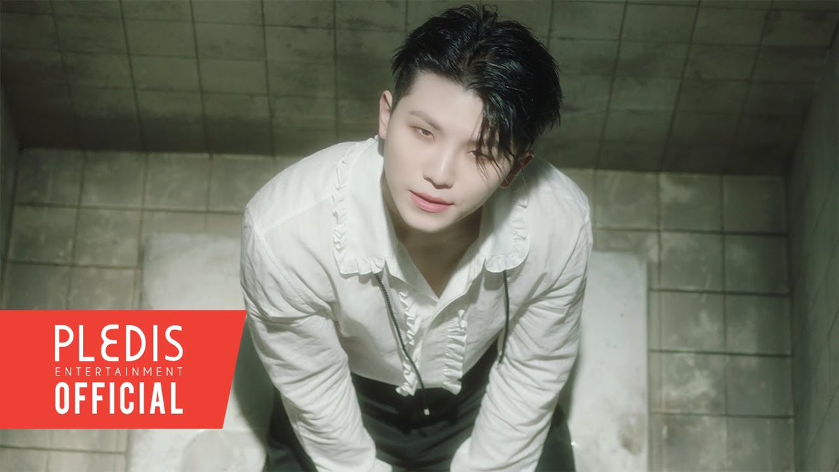 Promotional photo of a young man in a white ruffled shirt looking up at the camera in a tiled room, branded with a red 'PLEDIS ENTERTAINMENT OFFICIAL' logo in the lower left corner.