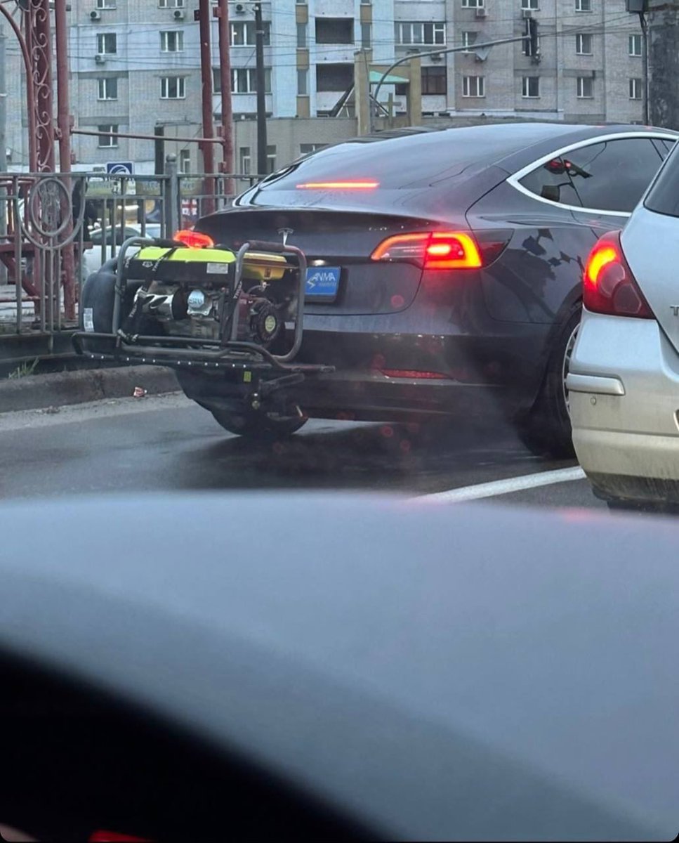 #Ukraine: Tesla that runs on electricity from a gasoline generator in #Kyiv. Here seen carrying its power supply.