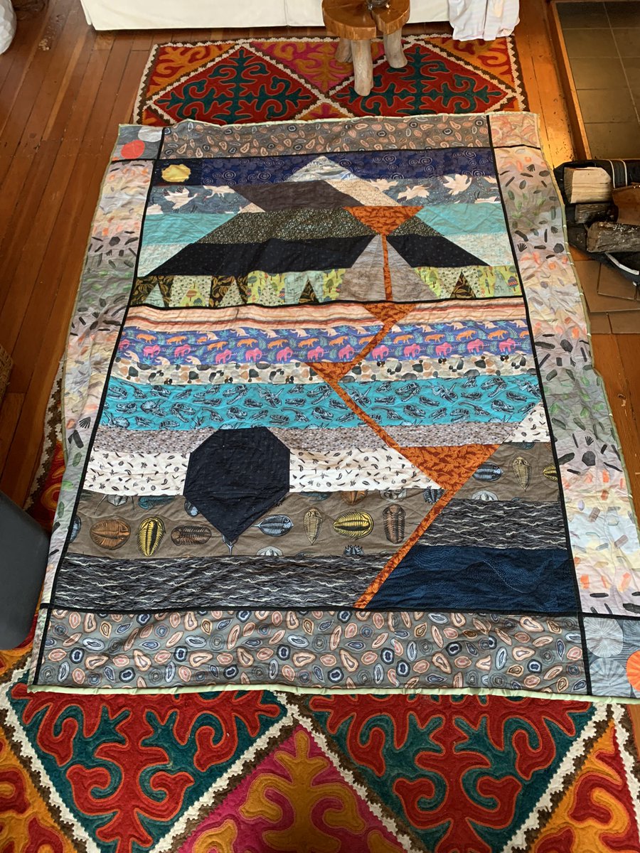 Paleowin's tweet photo. It’s done and gifted now! Geologic cross section quilt. Based on a sketch by my partner, designed, pieced, and quilted by me! Pluton and active magma chambers following a fault resulting in an erupting cinder cone in front of a larger dormant volcano. https://t.co/5tP6e3SMyr