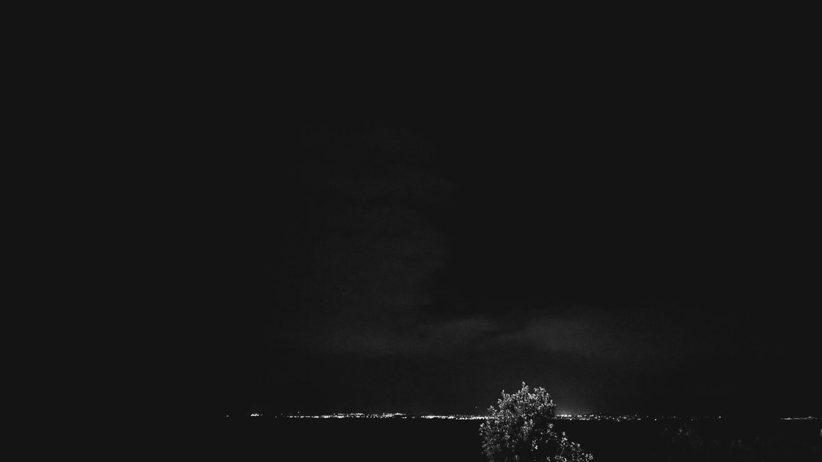 a black and white photograph of a coastline at night