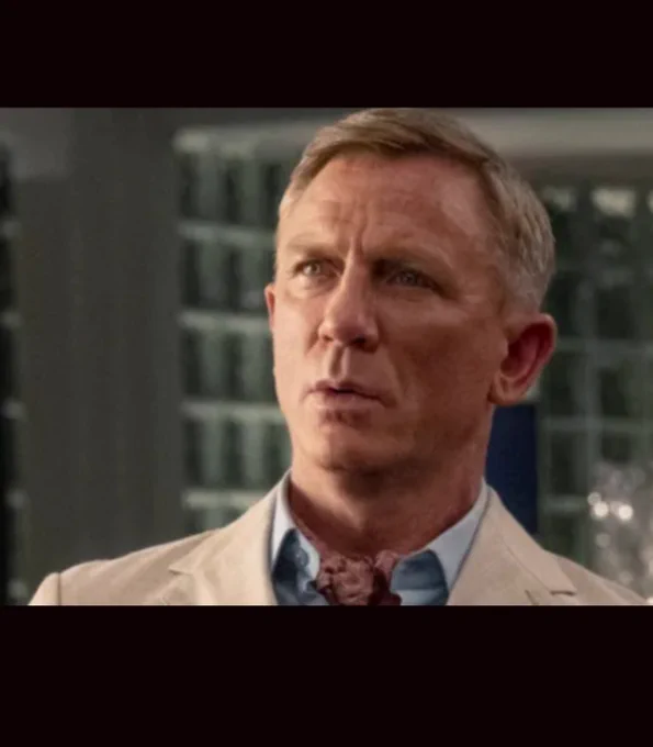 A close up of the face of actor Daniel Craig as detective Benoit Blanc, with a quizzical expression