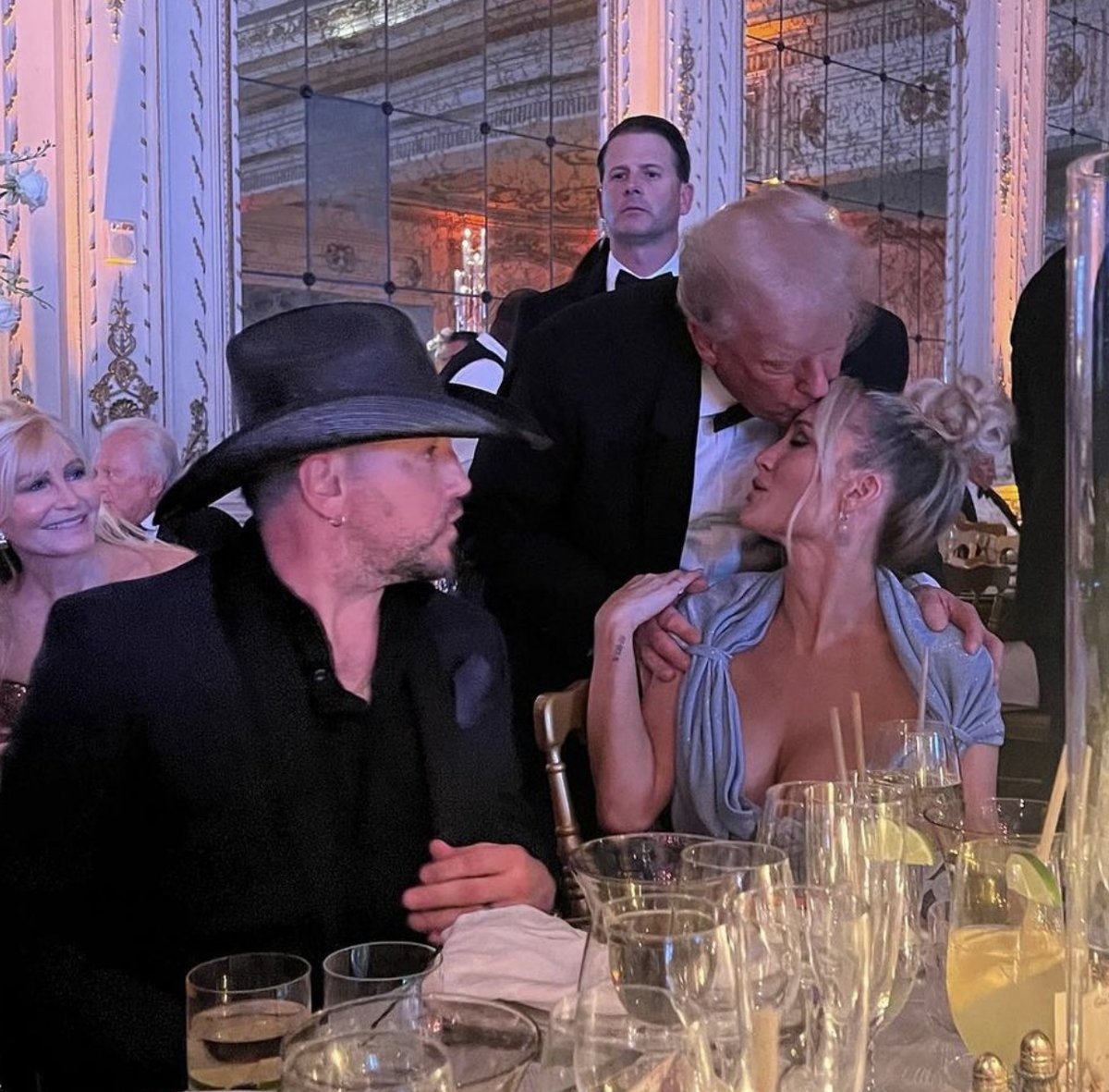 patriottakes's tweet photo. Trump kissing Brittany Aldean at Mar-a-Lago as her husband, Jason Aldean, watches. https://t.co/uchsQII5LV