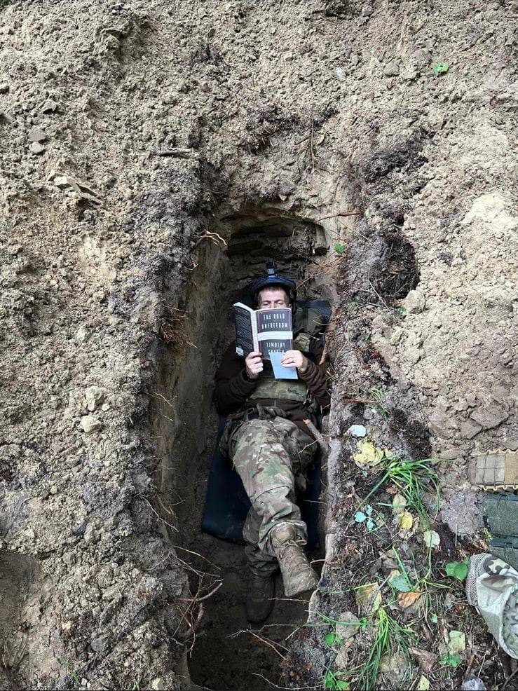nexta_tv's tweet photo. A Ukrainian soldier in a trench reading a book by American historian Timothy Snyder "The Road to Unfreedom". https://t.co/Bp79WquItl